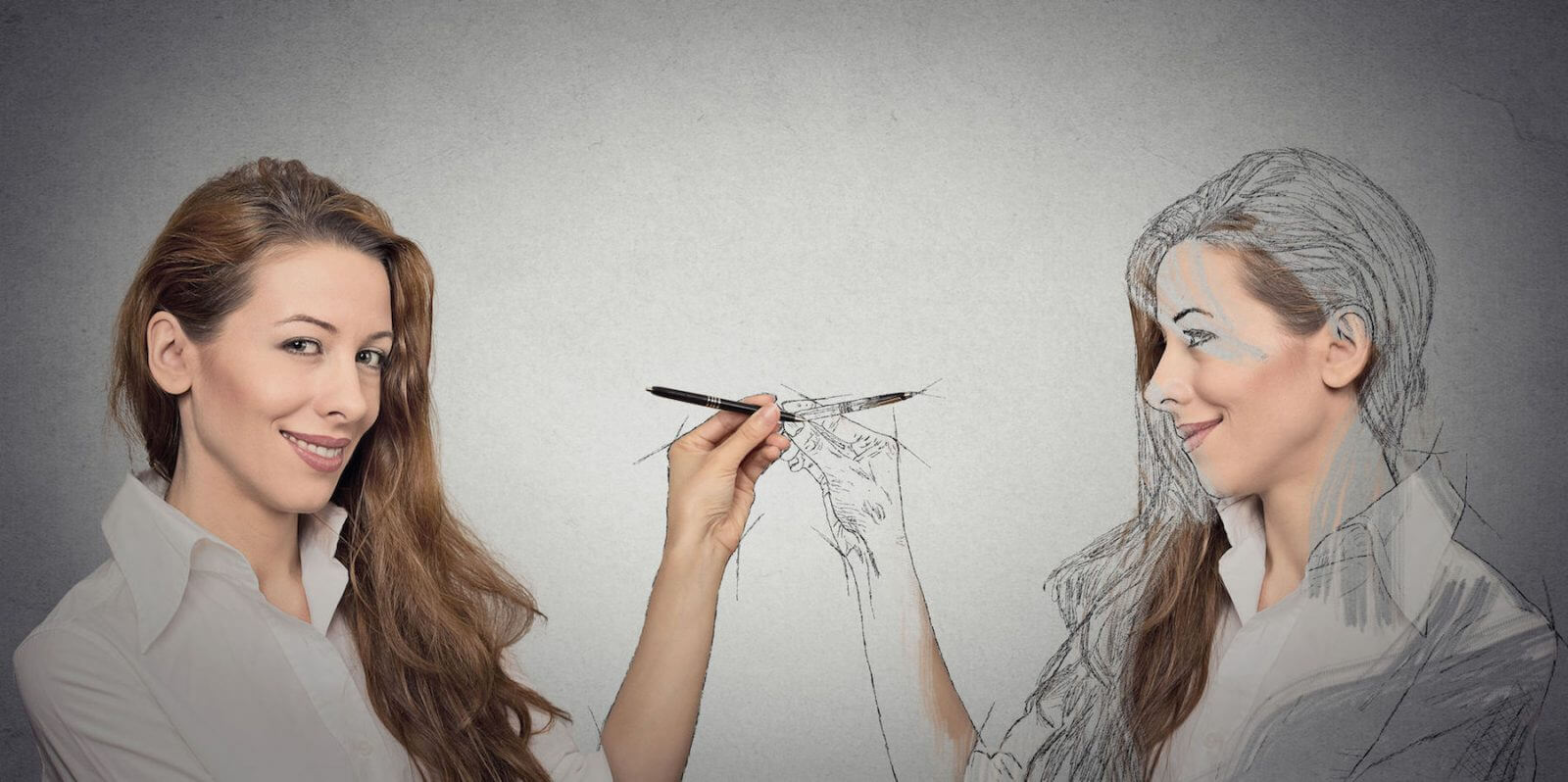 Create yourself, your future destiny, image, career concept. Attractive young woman drawing a picture, sketch of herself on grey wall background. Human face expressions, determination, creativity