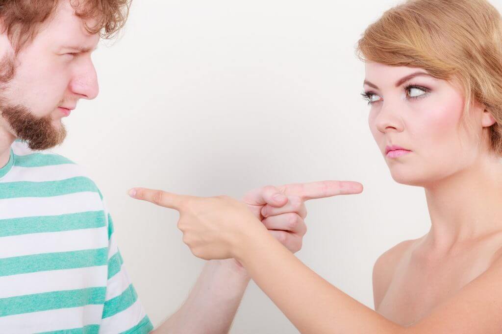 una pareja de chicos jóvenes se echa la culpa señalándose con el dedo y extendiendo su sentimiento de culpa